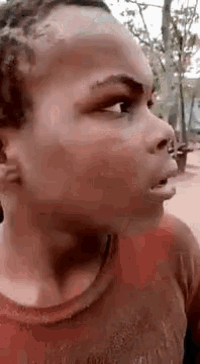 a young boy is making a funny face while wearing a red tank top .