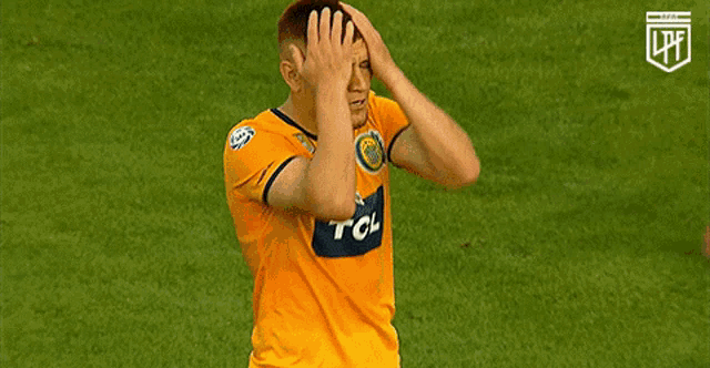a man wearing a yellow tcl jersey covering his face with his hands