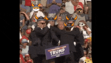 a man in a suit holds a trump sign in front of a crowd