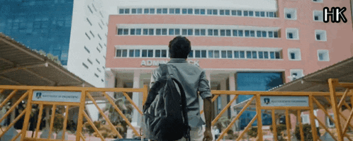 a man with a backpack stands in front of a administration building