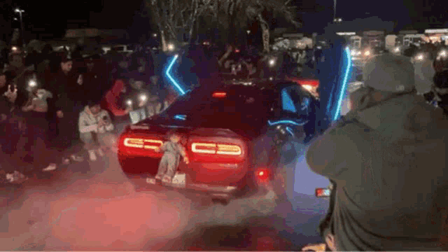 a man is taking a picture of a car with lights on the hood