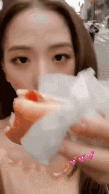 a close up of a woman eating a hot dog with hearts around her