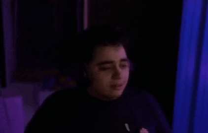 a man wearing headphones is sitting in a dark room and covering his ears .