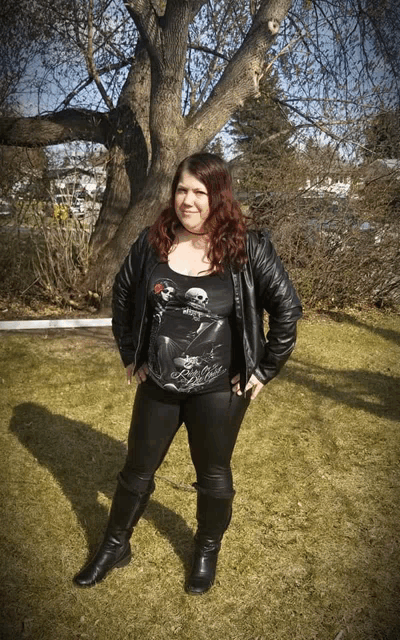a woman standing in front of a tree wearing a black shirt with a skeleton on it and a skull on it