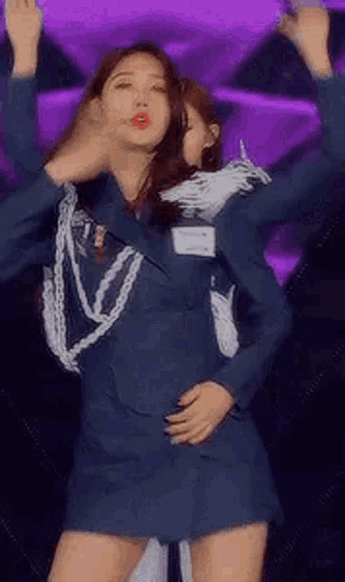 a woman in a blue dress is dancing on a stage with her arms in the air .