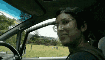 a woman wearing glasses and a baseball cap is sitting in a car