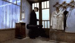 a man in a suit and hat is standing in a room