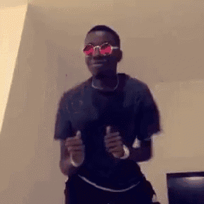 a man wearing sunglasses and a black shirt is dancing in a living room .