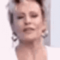 a close up of a woman 's face with her eyes closed . she is wearing earrings and a white shirt .
