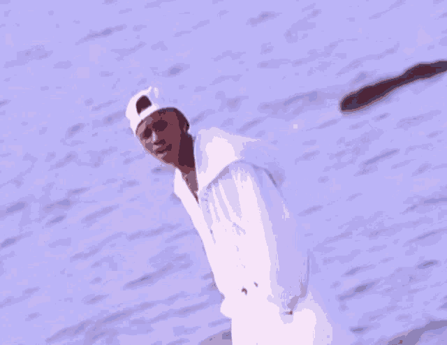 a man in a white hat is standing in front of a body of water ..