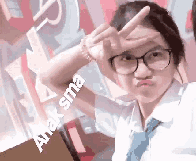 a girl wearing glasses making a peace sign with the word anaksma written below her