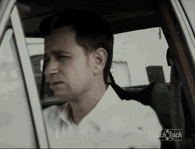 a man is sitting in a car with the words black luck on the bottom