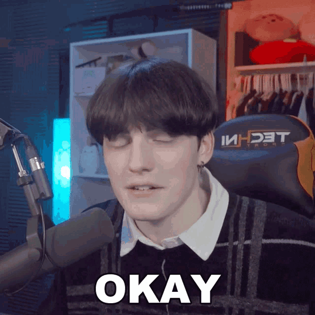 a man sitting in front of a microphone with his eyes closed and the word okay above his head
