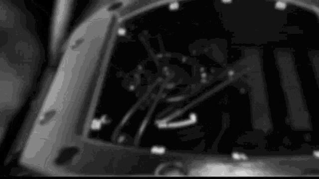 a black and white photo of a watch face with a blurred background .