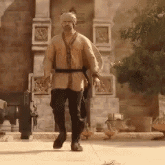 a man in a medieval outfit is walking down a sidewalk in front of a building .