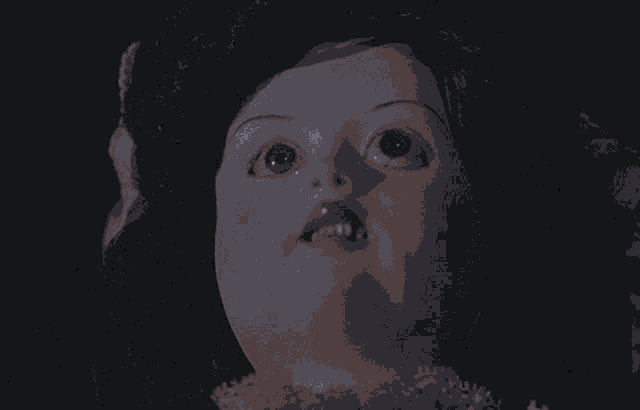 a close up of a doll 's face with black hair and pink lips