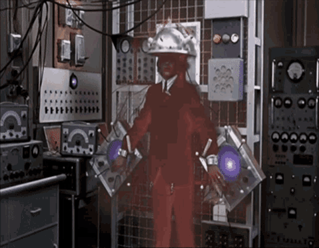 a man in a red suit is standing in a room with a lot of electrical equipment