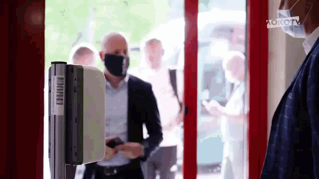 a man wearing a mask is standing in front of a machine with a barcode on it .
