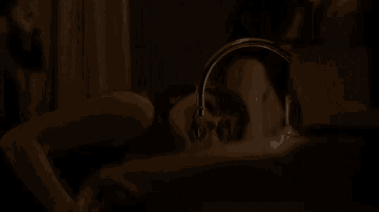 a woman is laying in a dark room looking at herself in a mirror .