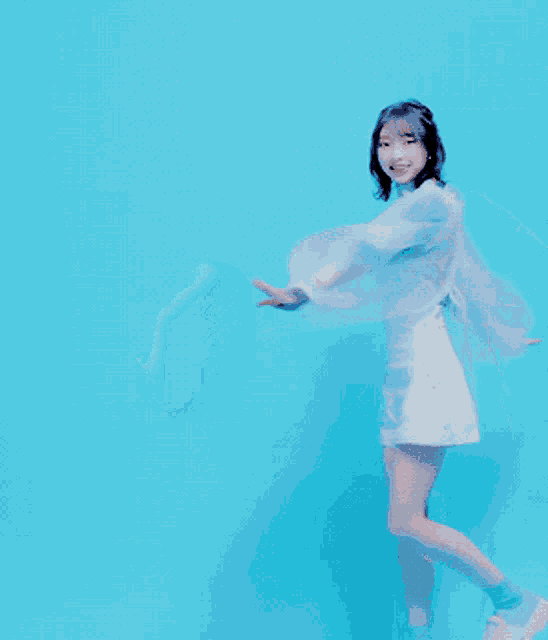 a girl in a blue shirt and white shorts is dancing in front of a blue background