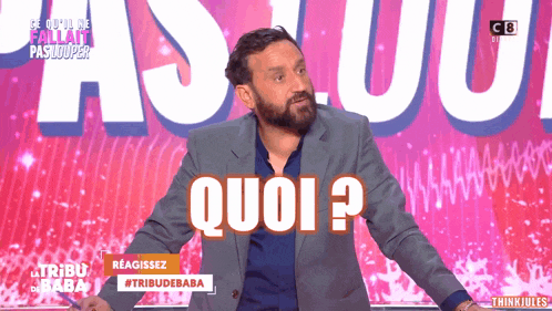 a man with a beard stands in front of a sign that says " quoi "