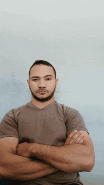 a man with his arms crossed in front of a blue wall
