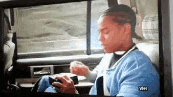 a woman in a blue shirt is sitting in the back seat of a car with a vhh logo on her shirt