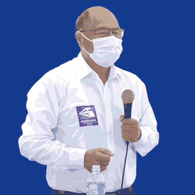 a man wearing a mask holds a microphone and a bottle