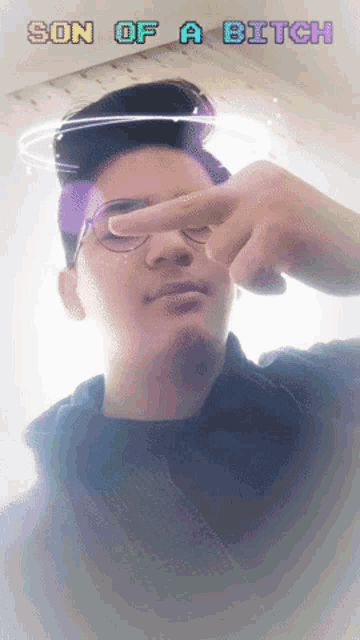 a man with glasses is making a peace sign with the words son of a bitch below him