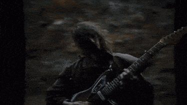 a man in a mask is playing a guitar in a dark room