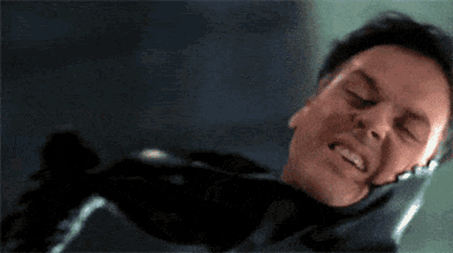 a man is laying down with his eyes closed