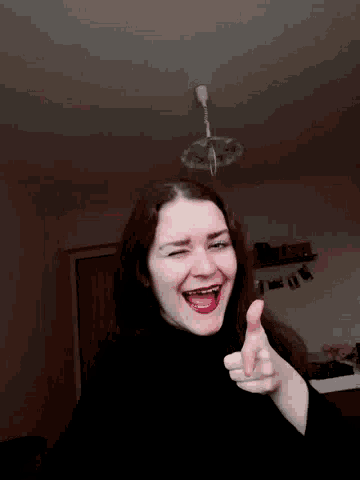 a woman with braces on her teeth is smiling and giving a thumbs up