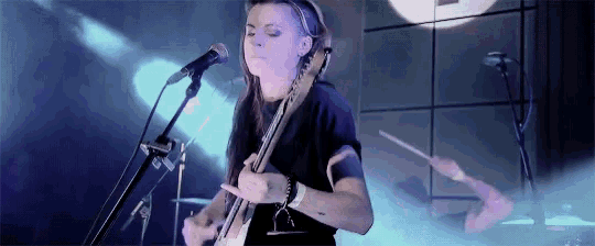 a woman is singing into a microphone while playing a guitar on a stage .