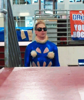 a man in a blue costume is standing in front of a sign that says " do you hoe "