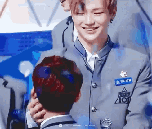 a man in a suit is hugging another man in front of a microphone and smiling .
