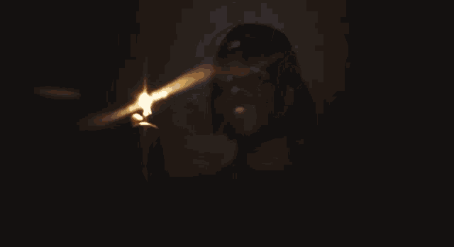 a man is lighting a cigarette with a lighter in the dark