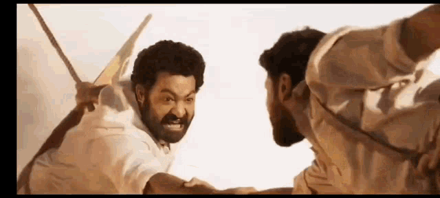 two men are fighting each other with swords in their hands .