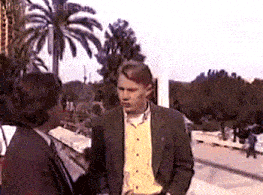 a man in a suit and tie is talking to a woman in a yellow shirt