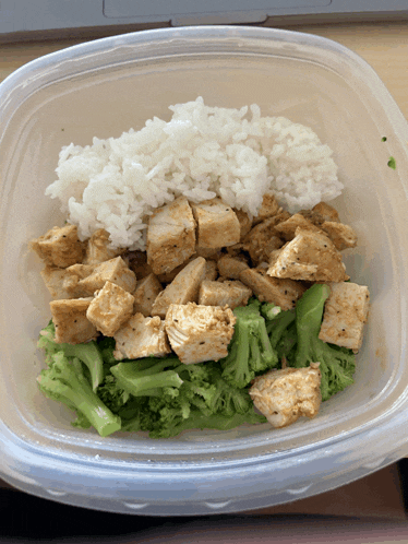a plastic container filled with rice broccoli and meat