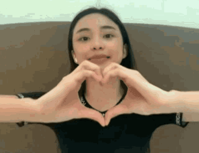 a woman is making a heart with her hands