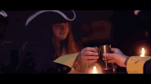 a man in a pirate hat holds a shot glass in his hand