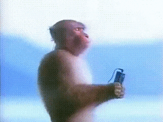 a monkey is standing in front of a blue background holding a cell phone .