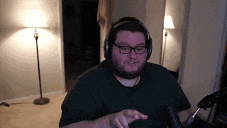a man wearing headphones and glasses is sitting in front of a microphone in a living room .