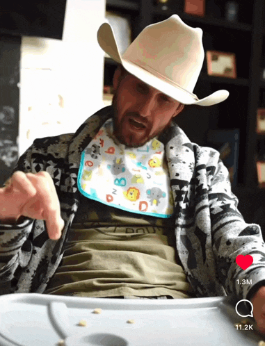 a man wearing a cowboy hat and a bib with the letters a b and d on it