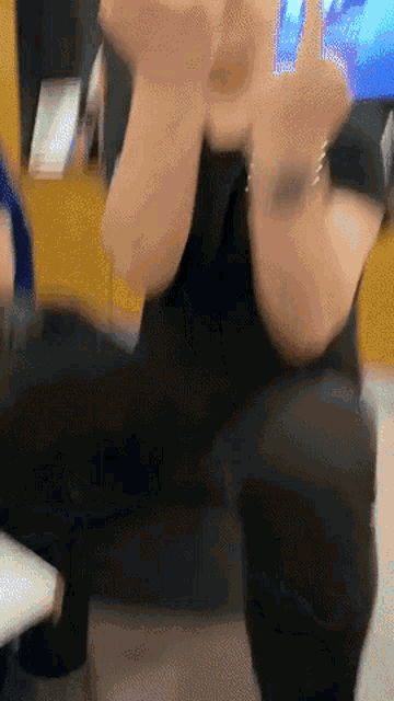 a man in a black shirt is sitting on a couch and giving a middle finger .