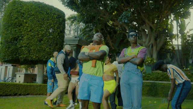 a group of people are standing in a park and one of them is wearing a yellow shirt that says ' a '