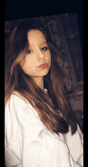 a girl with long brown hair is wearing a white hoodie