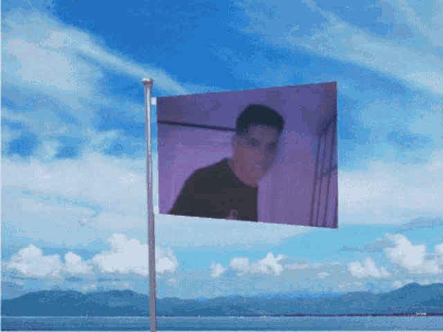 a purple flag with a picture of a man on it is flying in the wind