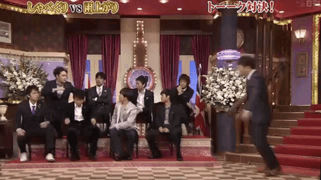a group of men are sitting on a stage with a sign that says vs.