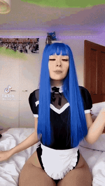 a girl with blue hair is sitting on a bed with a tiktok watermark